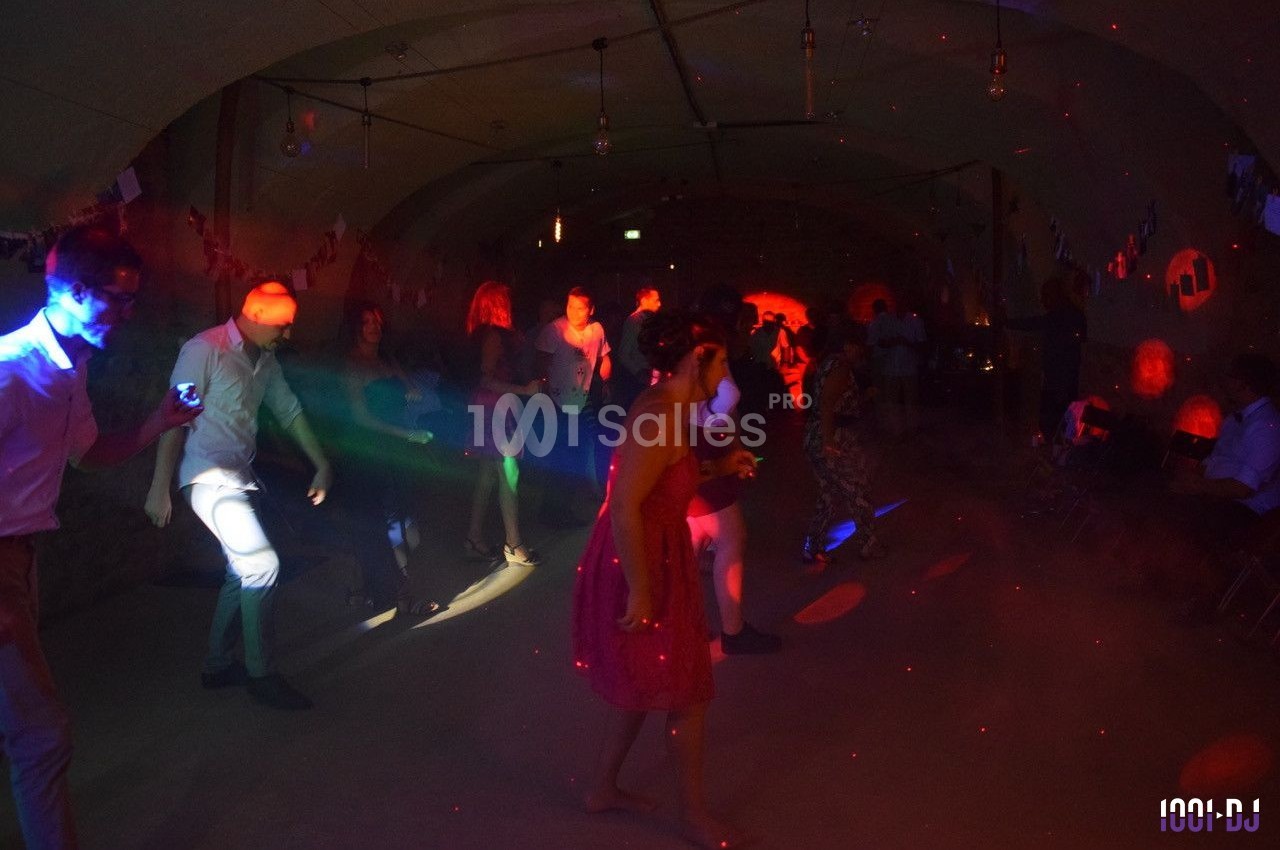 Personnes dansant sous des lumières colorées dans une salle sombre décorée pour une fête.