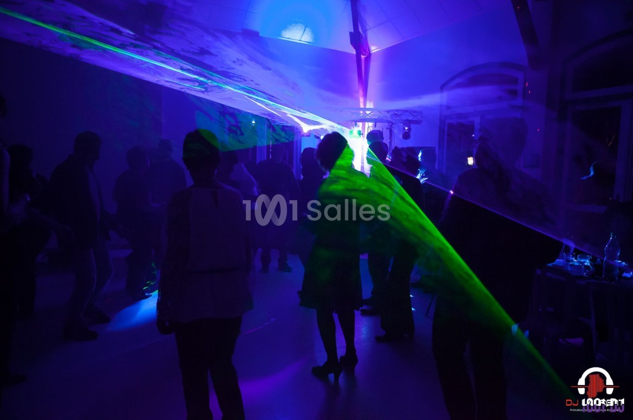 Personnes dansant dans une salle sombre, éclairée par des faisceaux lumineux colorés et des effets laser.