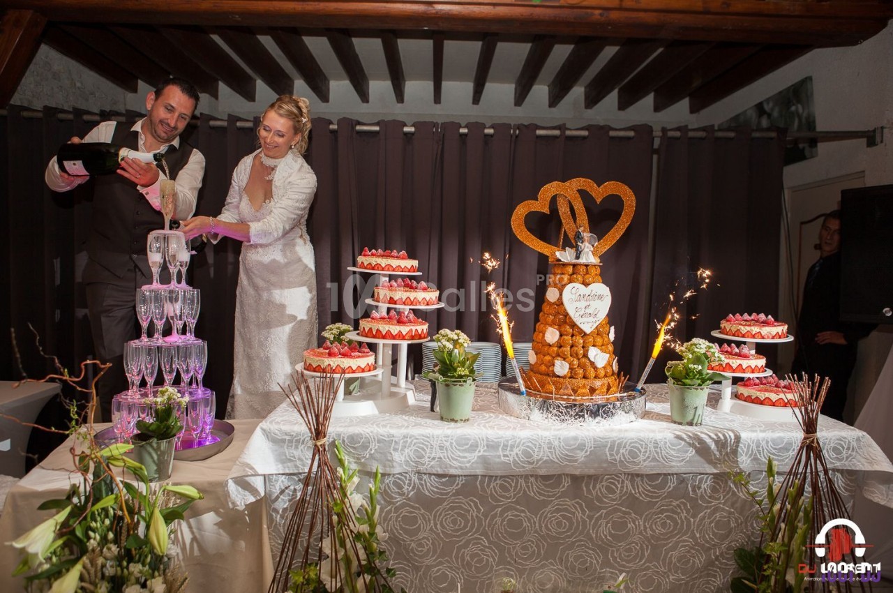 Un couple de mariés sert du champagne près d'une table décorée avec des desserts et une pièce montée.