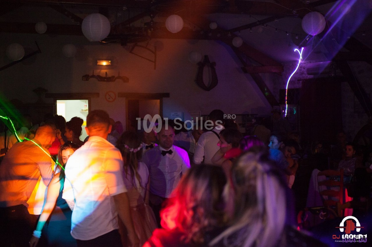 Groupe de personnes dans une salle sombre avec éclairages colorés, ambiance festive et décorations suspendues.