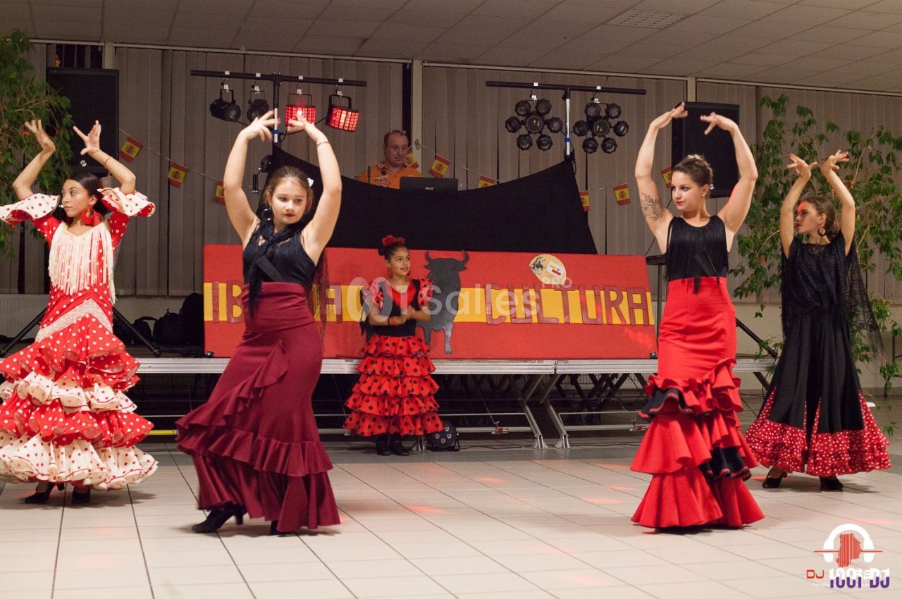 Des danseuses en tenue flamenco exécutent une chorégraphie sur une scène décorée aux couleurs espagnoles.