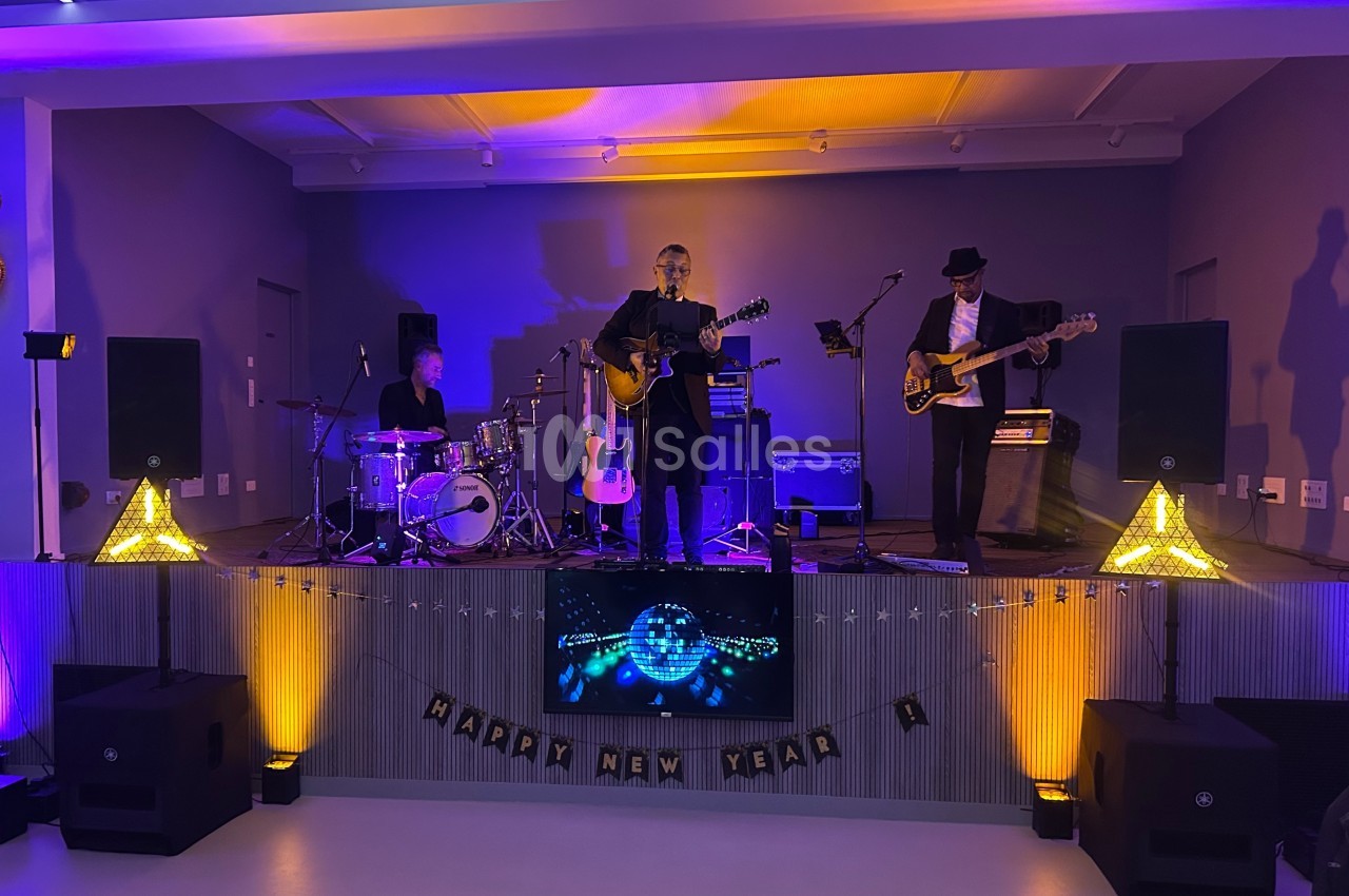 Un groupe de musiciens joue sur une scène éclairée, avec des décorations de Nouvel An en arrière-plan.
