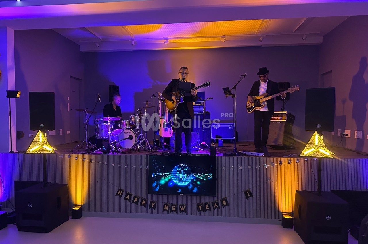 Un groupe de musiciens joue sur une scène éclairée, avec des décorations de Nouvel An en arrière-plan.