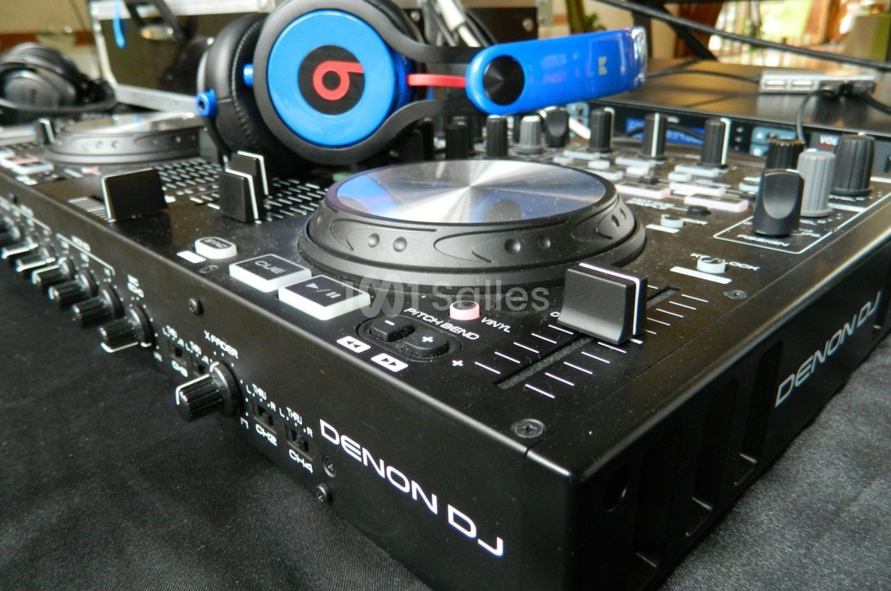 Table de mixage Denon DJ avec des casques audio posés dessus, entourée de divers boutons et commandes.