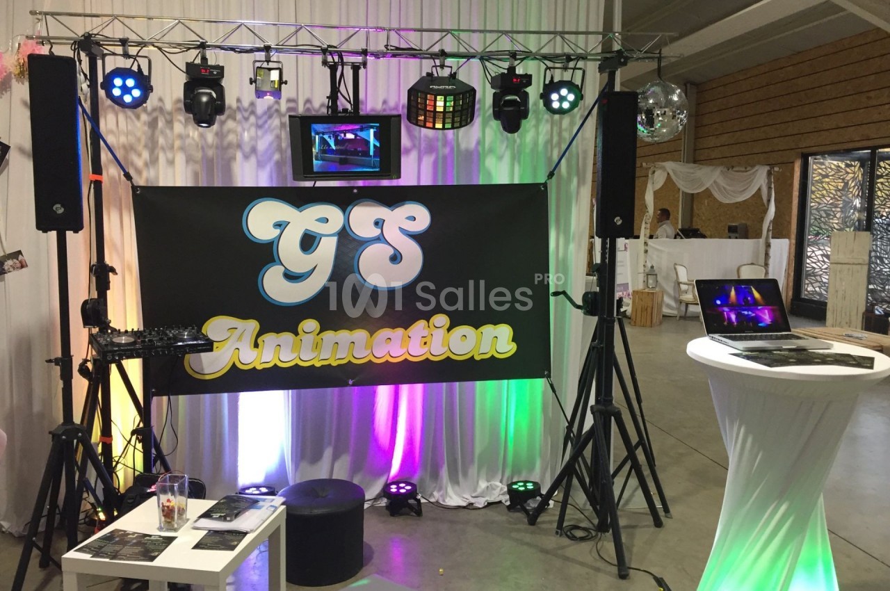 Équipement de sonorisation et éclairage installé pour un événement, avec une bannière ’GS Animation’ au centre.