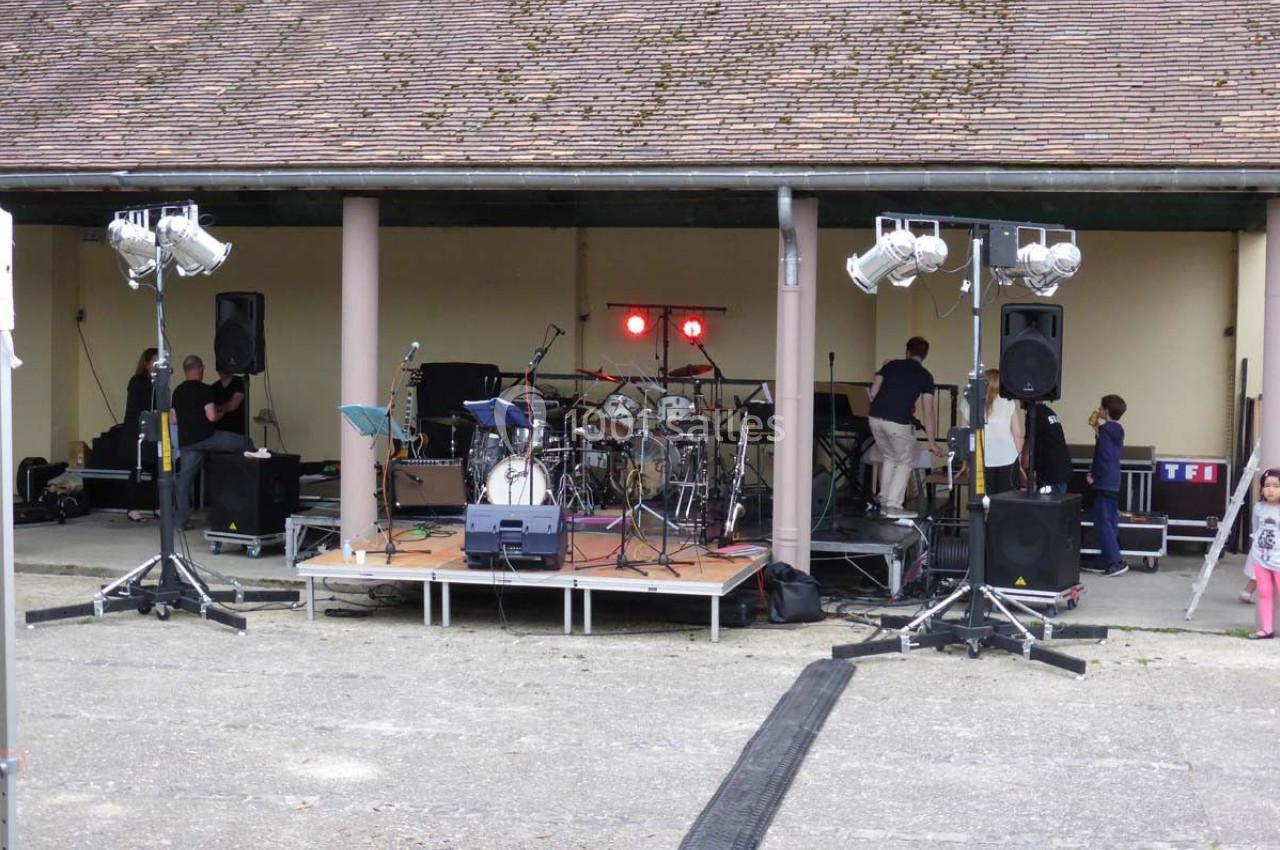 Scène extérieure avec instruments de musique installés, éclairages et techniciens préparant un événement.