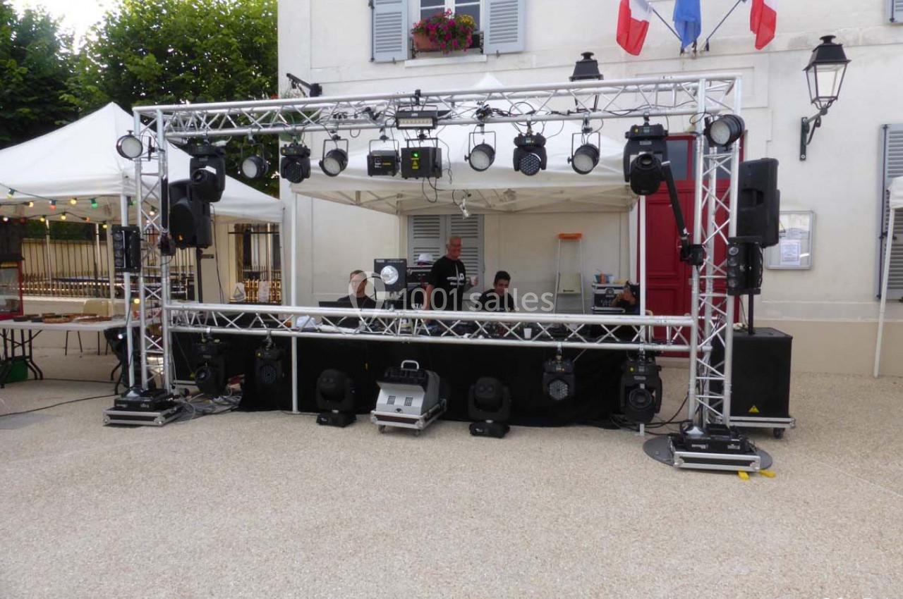 Structure métallique avec éclairages et matériel de sonorisation installée en extérieur devant un bâtiment.