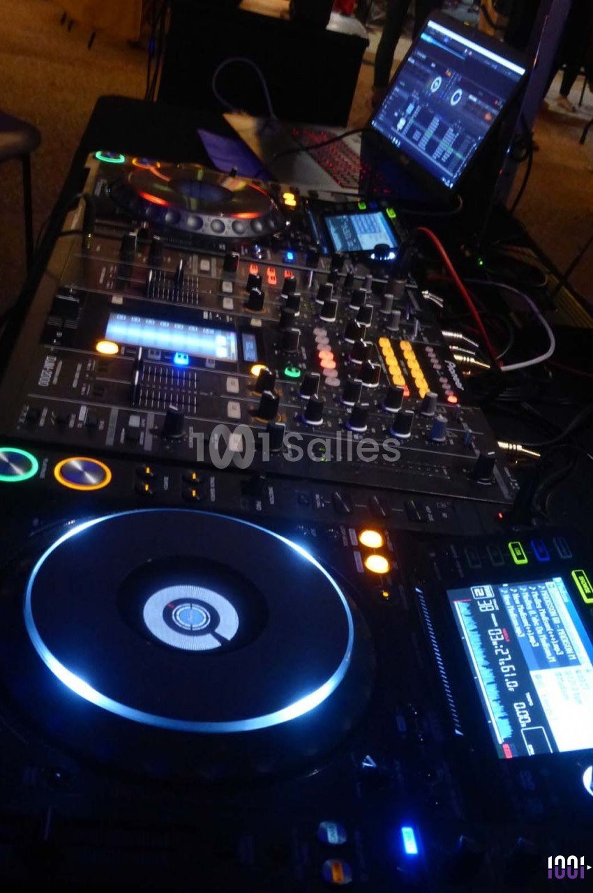 Équipement de DJ comprenant une table de mixage, des platines et un ordinateur portable en arrière-plan.