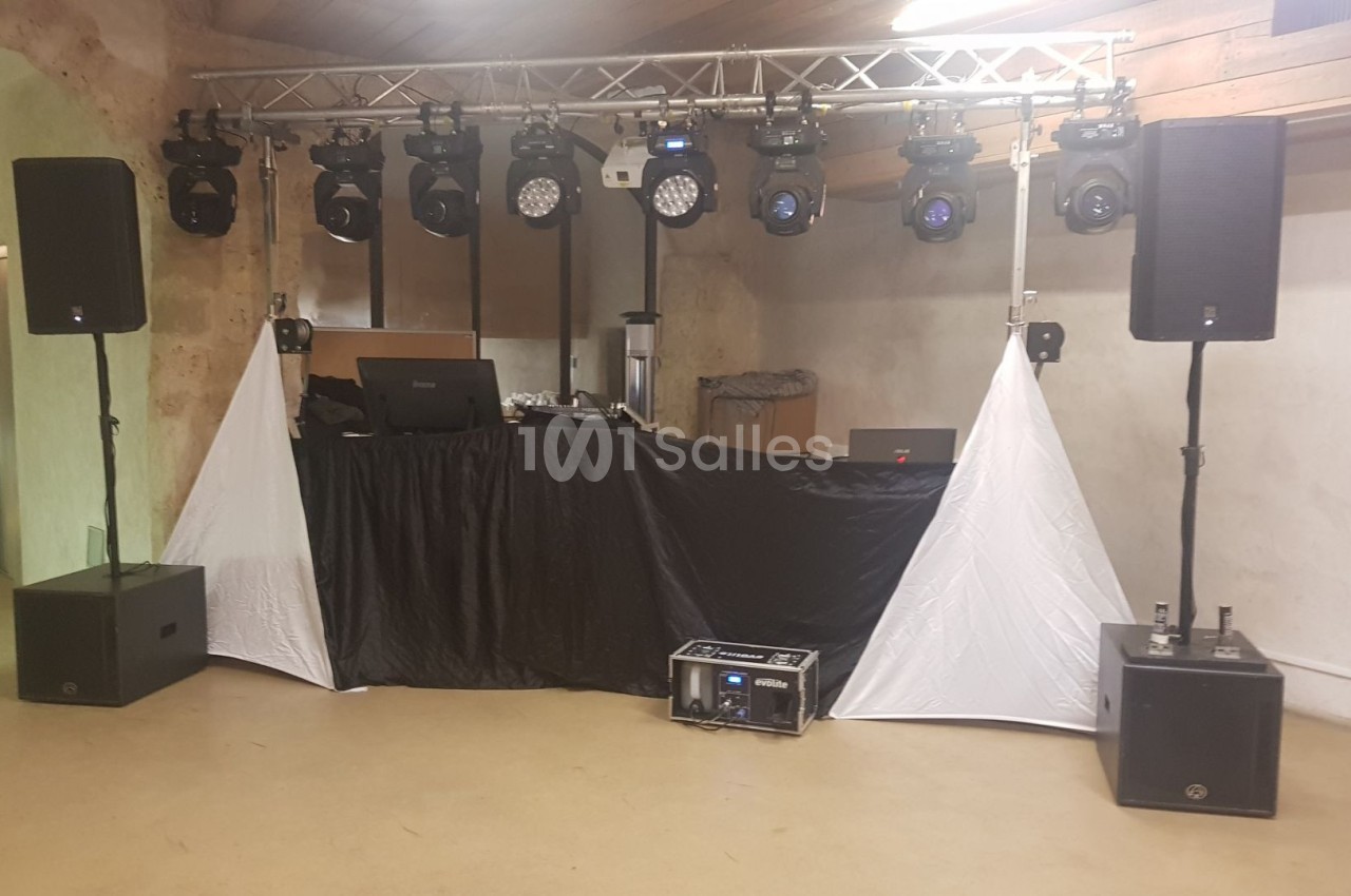 Installation de matériel de sonorisation et éclairage avec une table de mixage dans une salle intérieure.