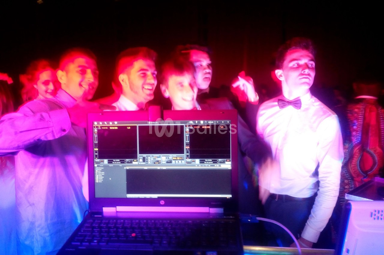 Des jeunes hommes dansent et posent joyeusement devant un ordinateur portable affichant un logiciel de mixage.