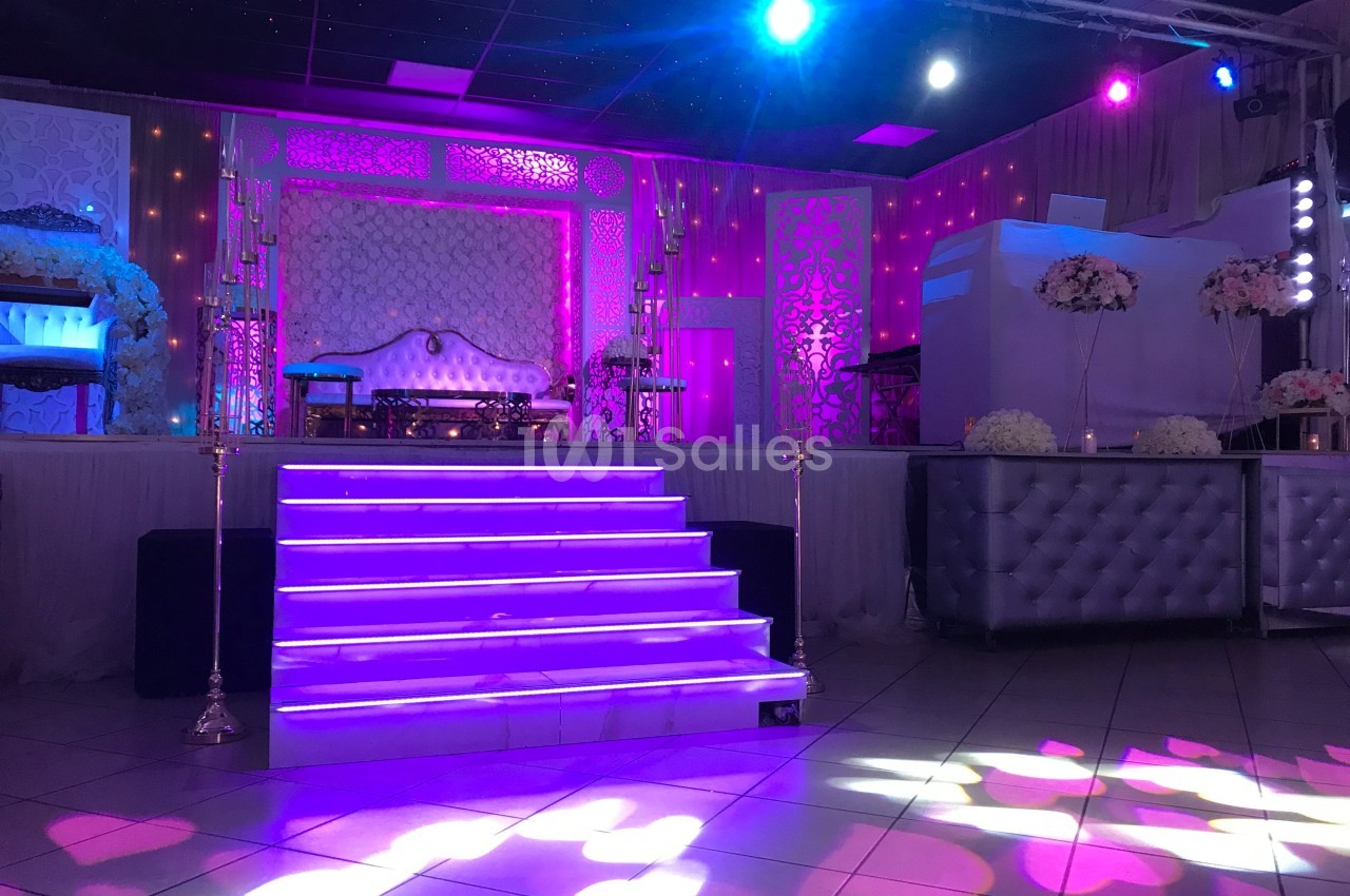 Scène décorée avec des lumières violettes, escalier central illuminé et mobilier élégant dans une salle de réception.