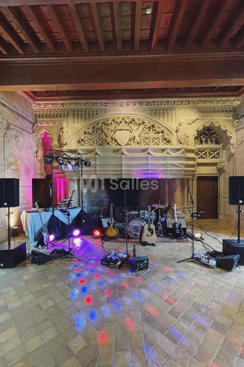 Scène musicale installée dans une salle au décor ancien avec instruments, éclairages et équipements audio.