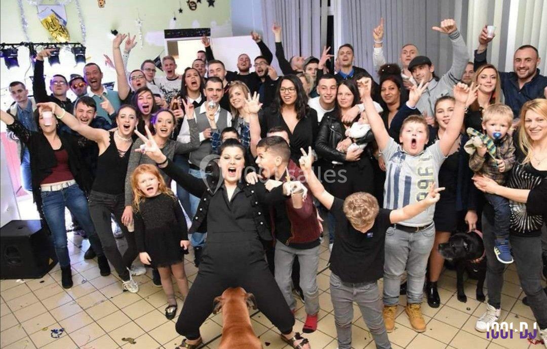 Un grand groupe de personnes de tous âges posant joyeusement dans une salle décorée pour une fête.