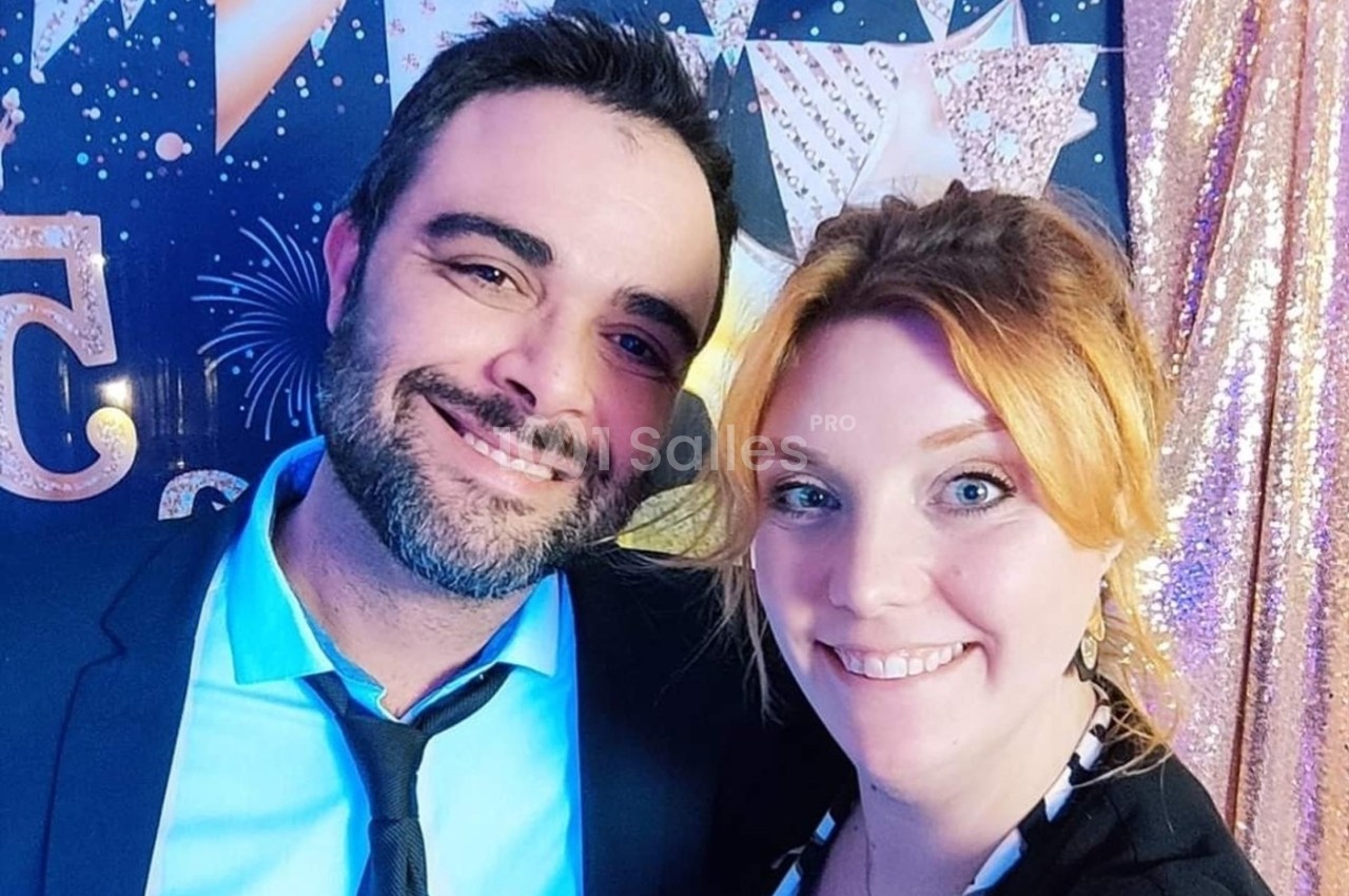 Un homme et une femme souriants posent devant un fond décoré de motifs étoilés et scintillants.
