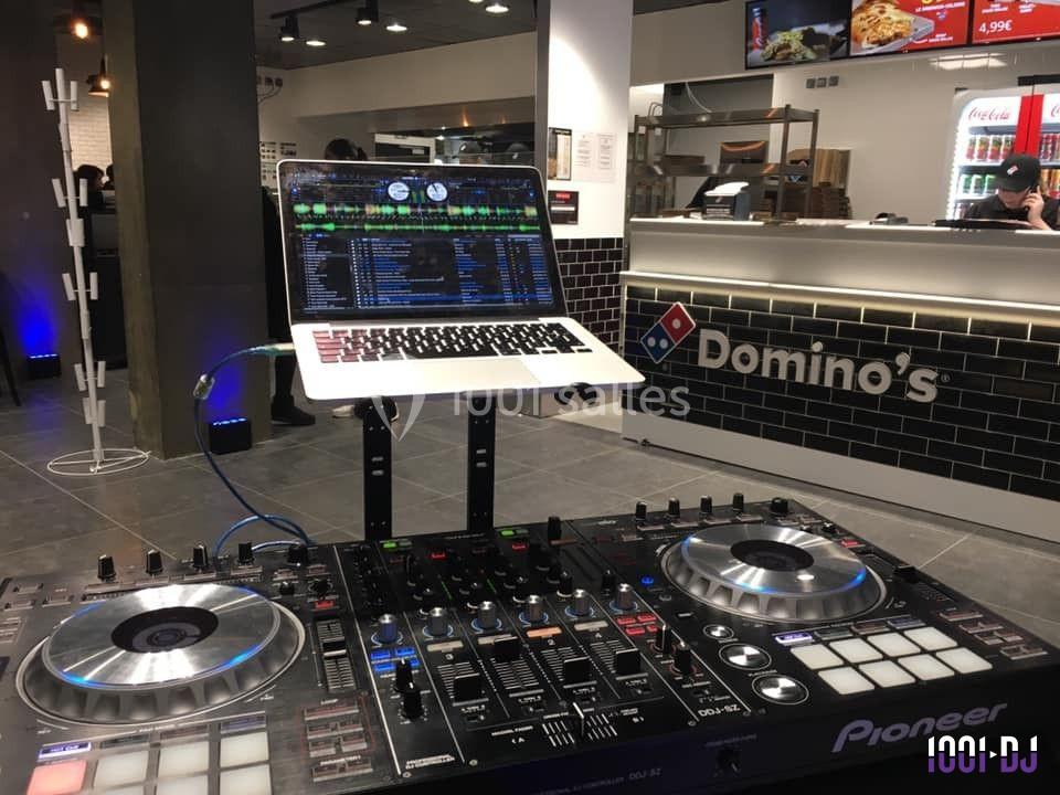 Table de mixage avec ordinateur portable en fonctionnement dans un restaurant Domino's Pizza moderne.