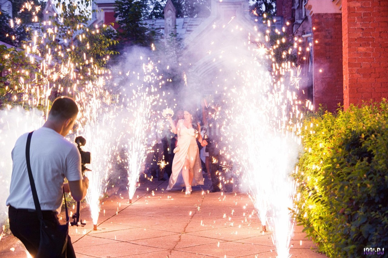 Un couple avance sous des gerbes d'étincelles lors d'une célébration, photographié par un professionnel.
