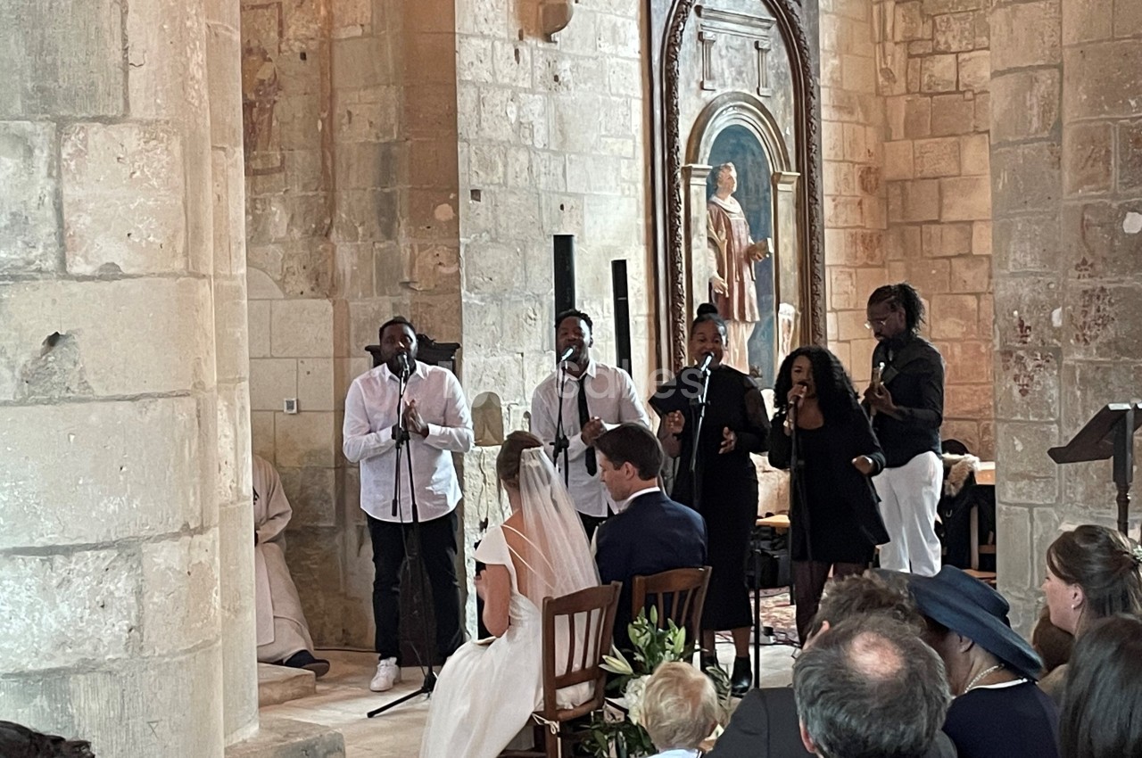 Un groupe de chanteurs interprète un morceau lors d'une cérémonie de mariage dans une église en pierre.