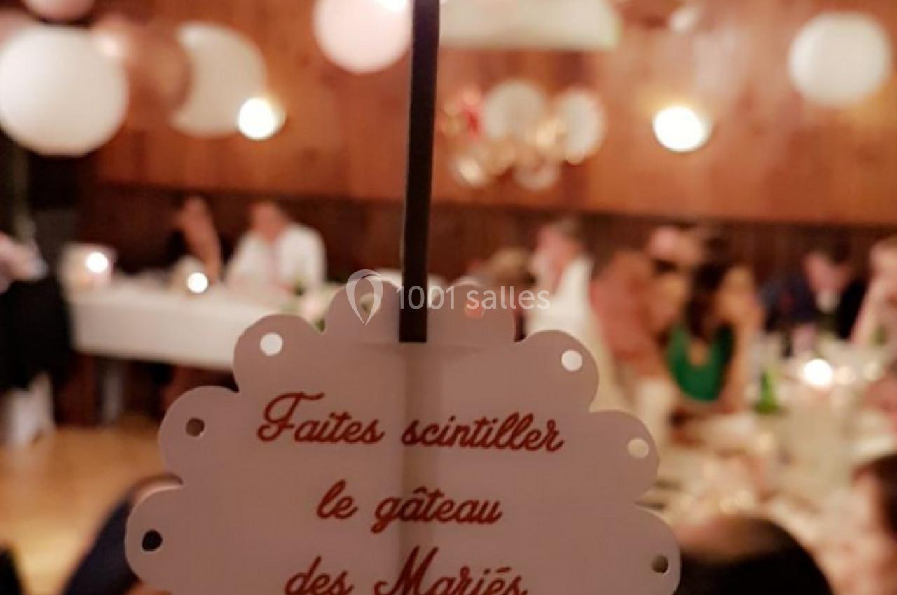 Une étincelle décorative avec un message invitant à faire un vœu pour les mariés, dans une salle de réception festive.