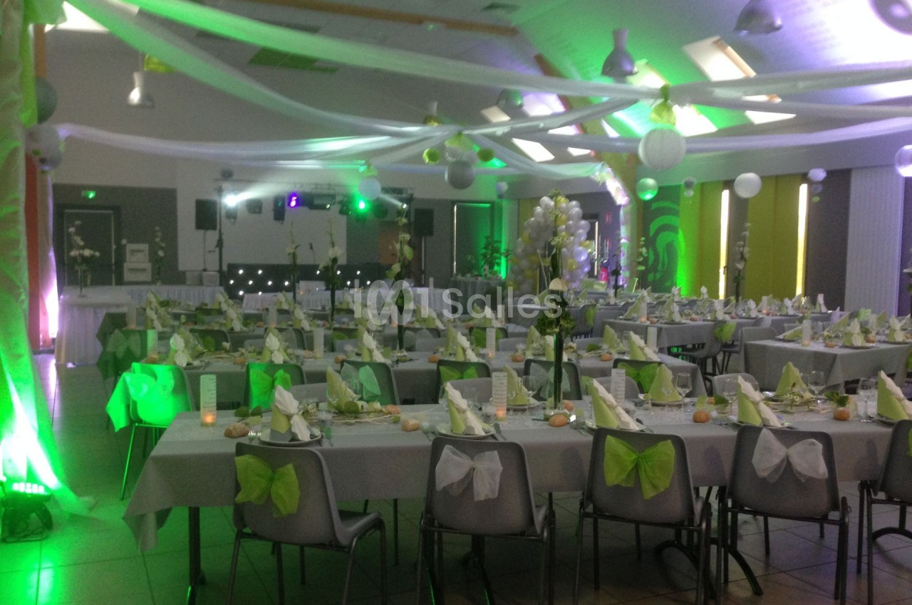 Salle de réception décorée en vert et blanc avec des tables dressées pour un événement festif.