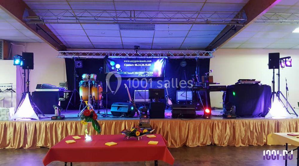 Scène équipée d'instruments de musique et de lumières colorées dans une salle avec tables décorées.