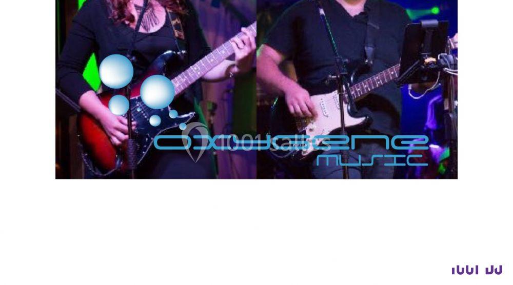 Deux musiciens jouant de la guitare électrique sur une scène avec des lumières colorées en arrière-plan.