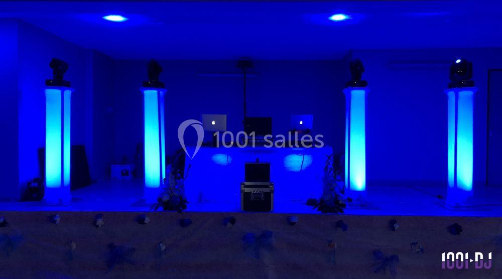 Installation de matériel de DJ avec éclairage bleu, comprenant une table de mixage et des colonnes lumineuses.