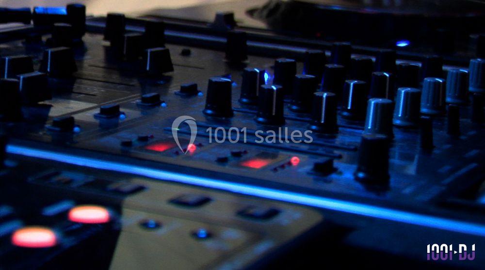 Table de mixage avec plusieurs boutons et curseurs éclairés, utilisée pour le mixage audio en studio ou en live.