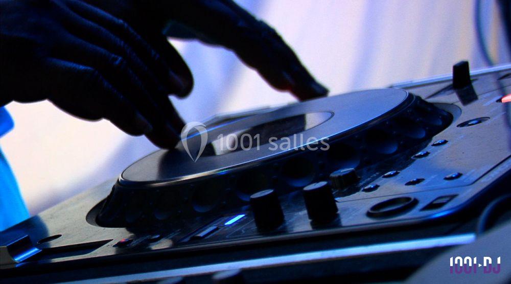 Mains ajustant les commandes d'une table de mixage DJ sous un éclairage tamisé.