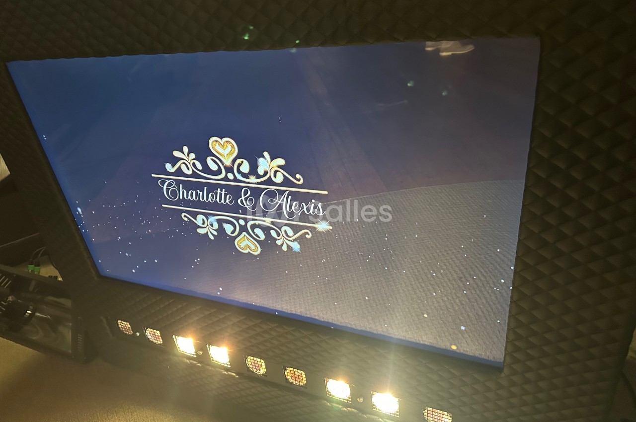 Écran affichant une animation avec les prénoms ’Charlotte et Alexis’ entourés de motifs décoratifs dorés.