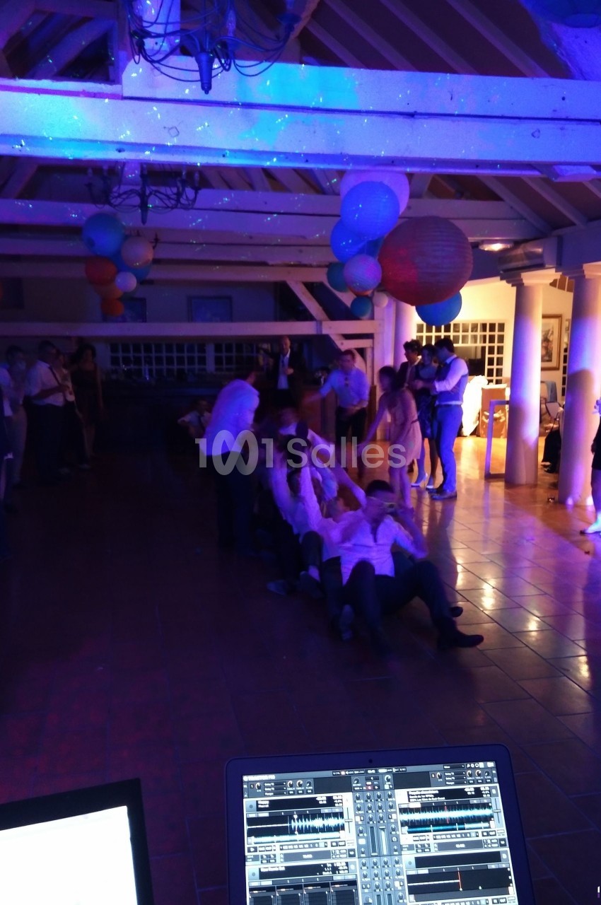 Des personnes participent à un jeu collectif dans une salle décorée, éclairée par des lumières colorées.