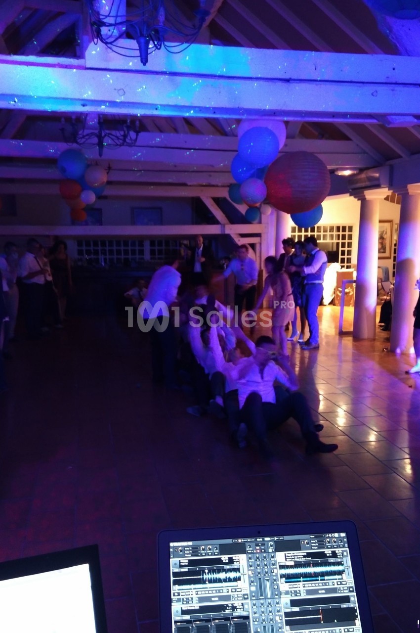 Des personnes participent à un jeu collectif dans une salle décorée, éclairée par des lumières colorées.