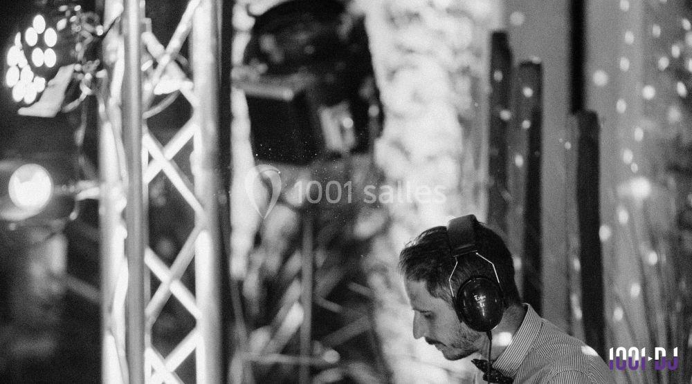 Un DJ portant un casque audio mixe de la musique dans un environnement éclairé par des projecteurs.