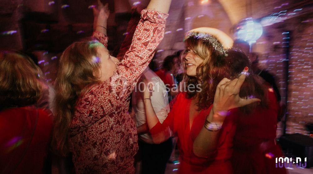 Deux femmes dansent joyeusement sous des lumières colorées dans une ambiance festive.