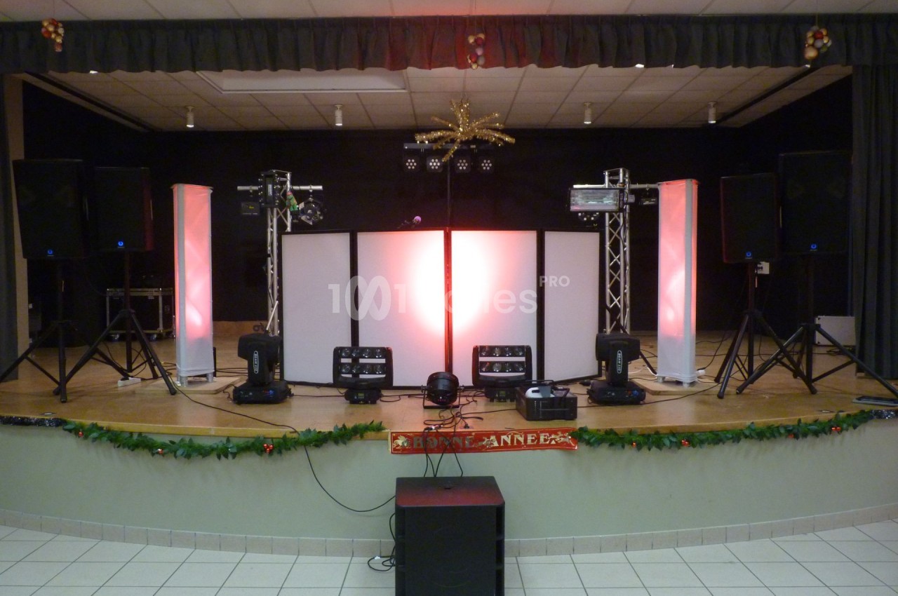 Configuration d'une scène avec éclairages colorés, haut-parleurs et équipements audio-visuels dans une salle de spectacle.