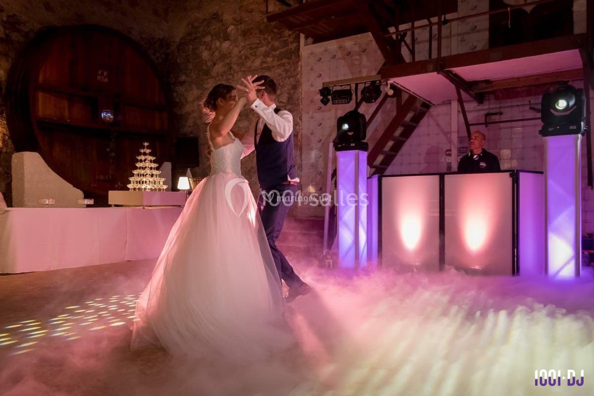 Un couple danse dans une salle éclairée avec des lumières colorées et un sol recouvert de fumée.