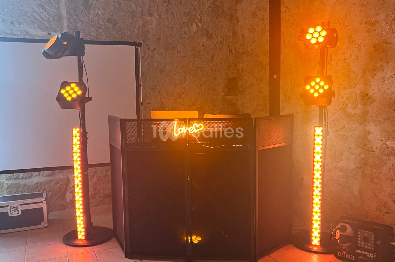Installation de matériel de sonorisation et éclairage avec projecteurs orange et panneau lumineux ’love’.