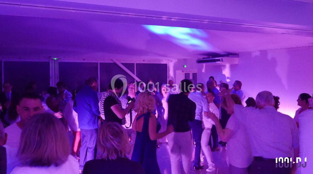 Personnes dansant dans une salle éclairée par des lumières violettes lors d'un événement festif.