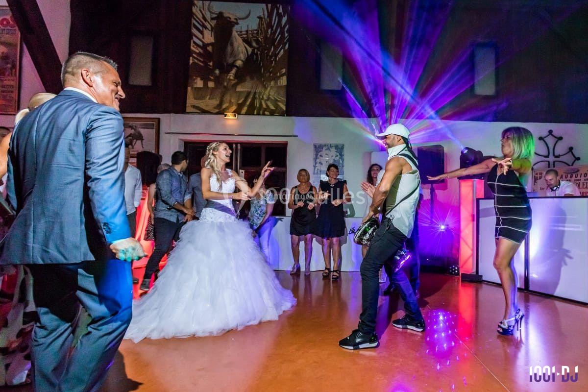 Des invités dansent lors d'une réception de mariage avec un guitariste et des jeux de lumière colorés.