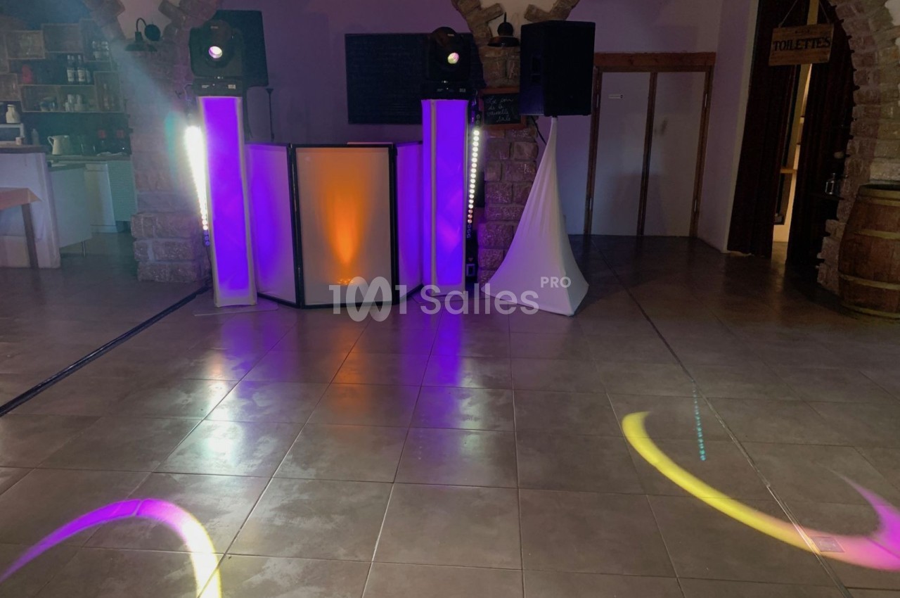 Équipement de sonorisation et éclairage coloré installé dans une salle avec sol carrelé et murs en pierre.