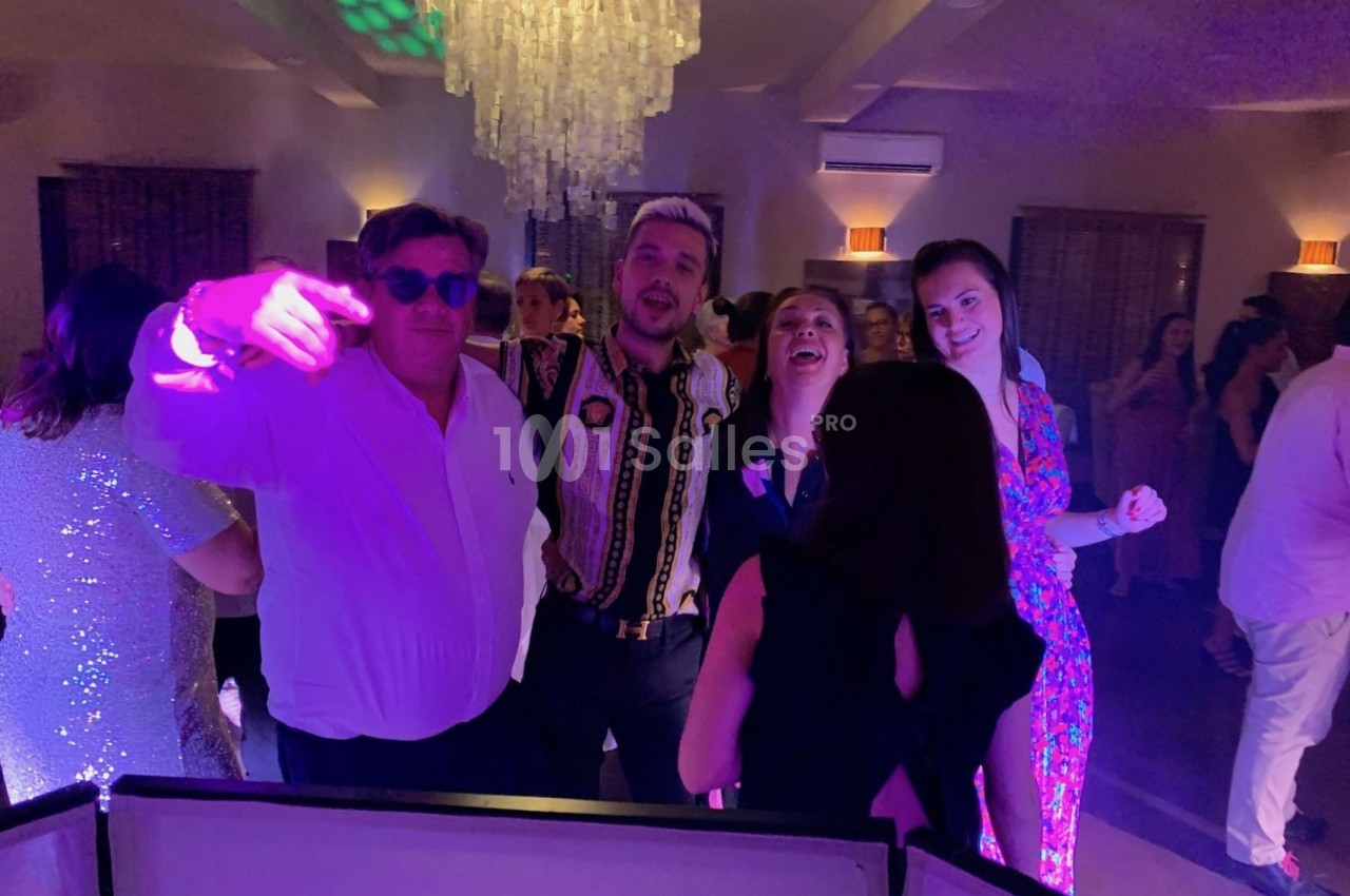 Groupe de personnes dansant et posant joyeusement sous des lumières colorées lors d'une soirée festive.