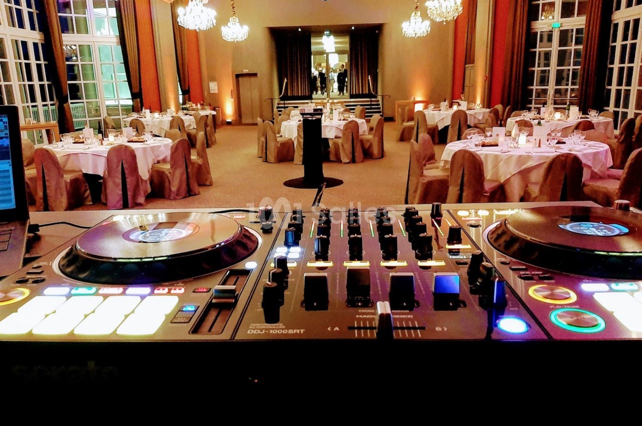 Console de DJ allumée au premier plan, avec une salle de réception élégamment décorée en arrière-plan.