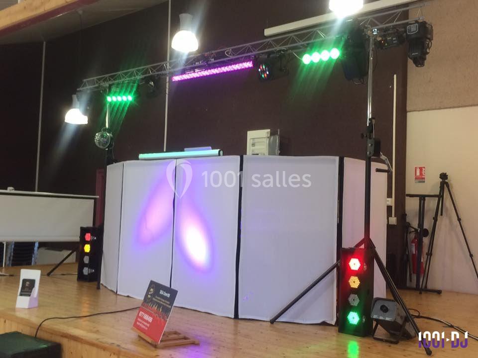 Installation de matériel de sonorisation et d'éclairage sur une scène avec une table de mixage éclairée.