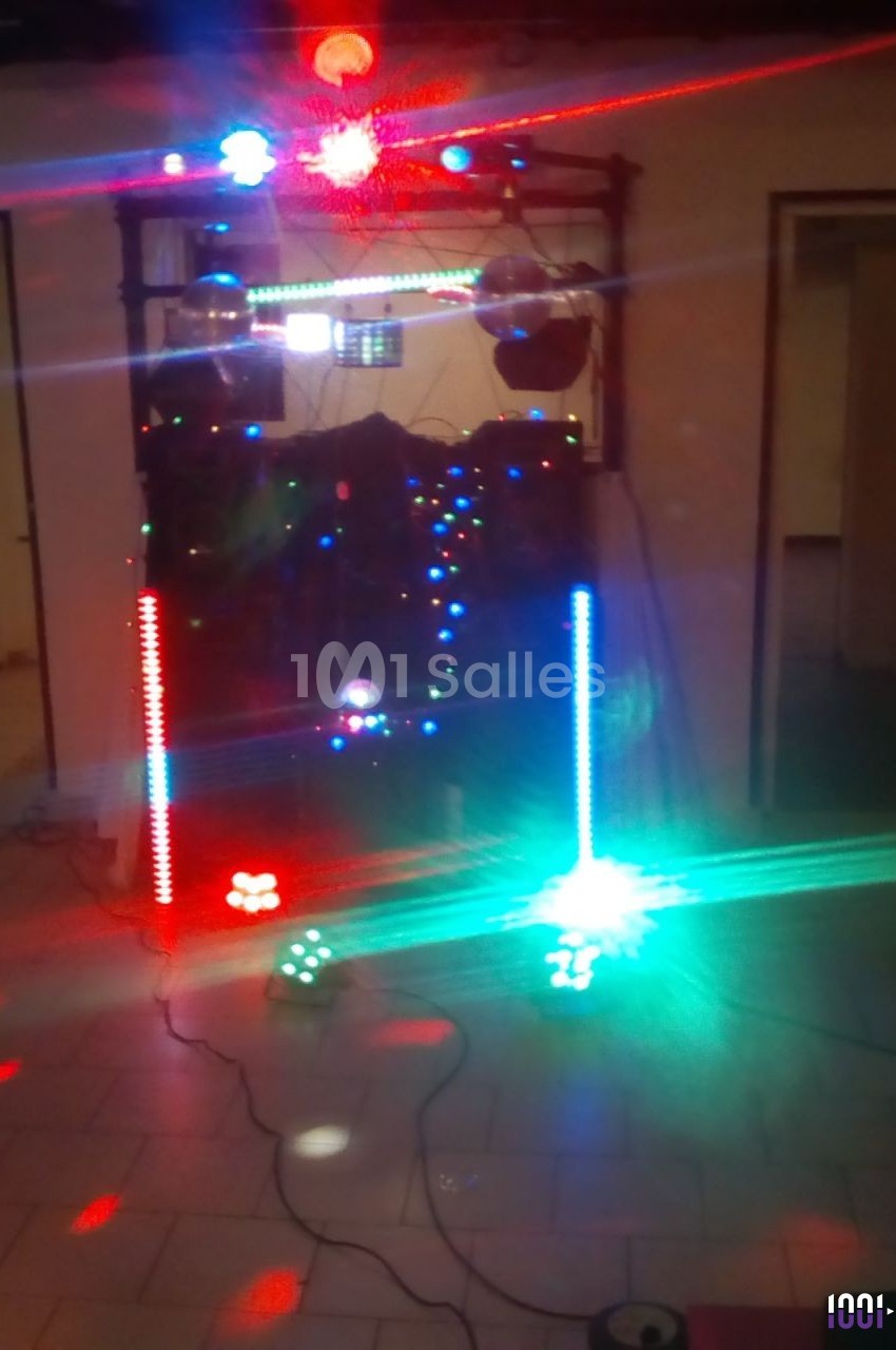 Installation de matériel de sonorisation et éclairage coloré dans une pièce, avec faisceaux lumineux rouges et verts.