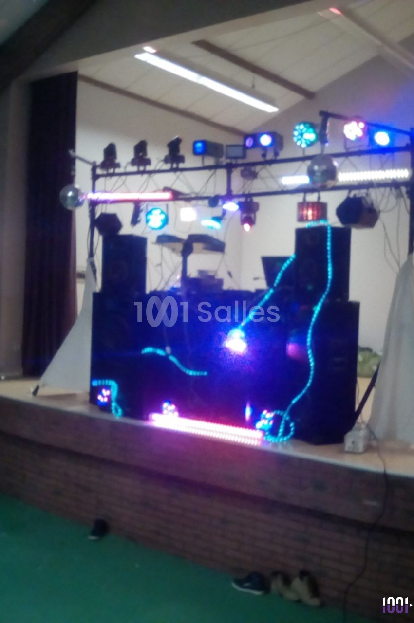 Installation de matériel de sonorisation et éclairage coloré sur une scène dans une salle intérieure.