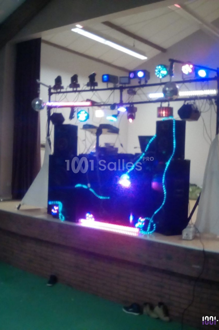 Installation de matériel de sonorisation et éclairage coloré sur une scène dans une salle intérieure.