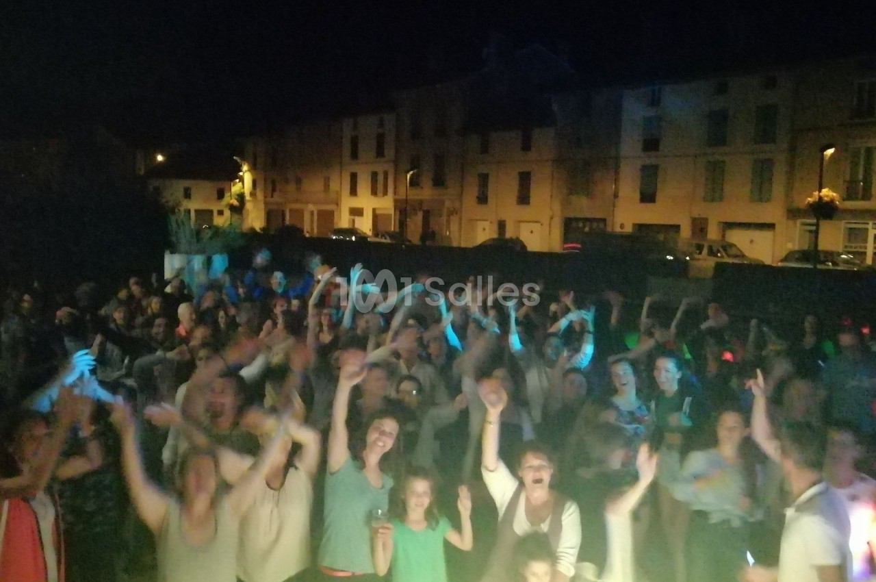 Groupe de personnes rassemblées en plein air la nuit, levant les bras dans une ambiance festive.