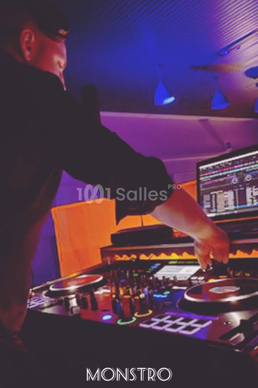Un DJ mixant de la musique sur une table de mixage éclairée par des lumières colorées dans une ambiance nocturne.
