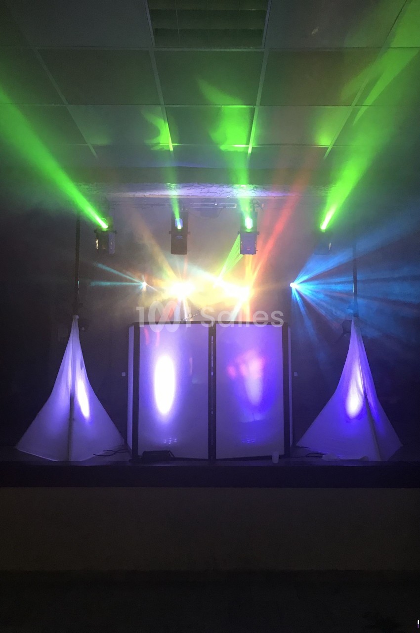 Jeu de lumières colorées projetées sur une scène avec des structures blanches en arrière-plan.