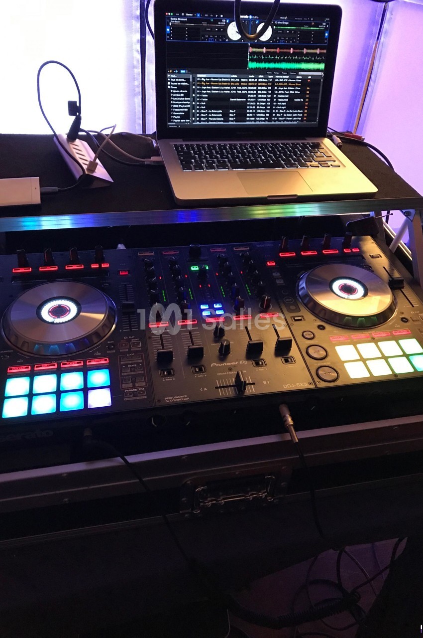 Table de mixage DJ avec platines lumineuses et un ordinateur portable affichant un logiciel de mixage.
