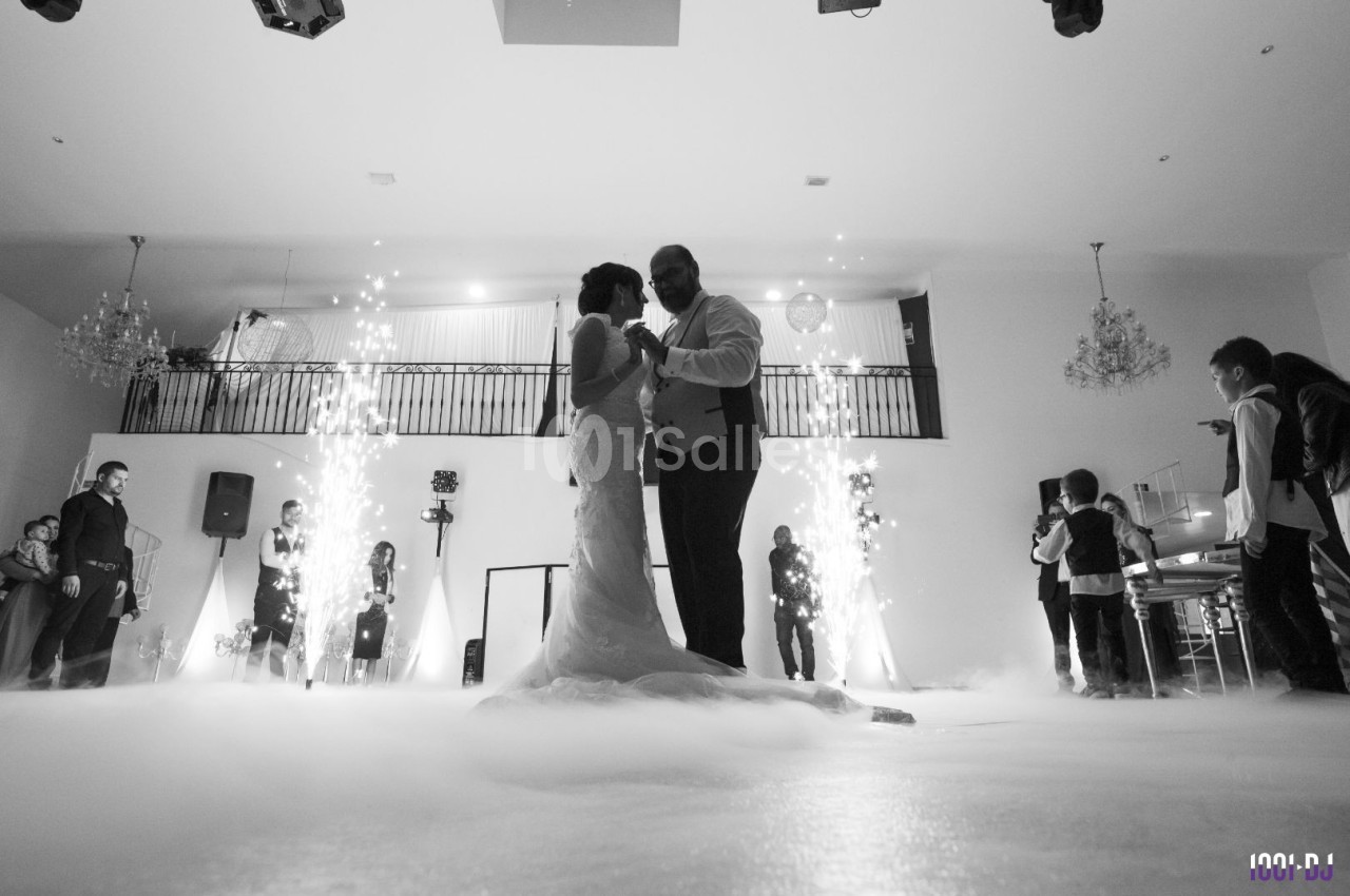 Un couple danse au milieu d'une salle décorée, entouré de fumée et d'effets lumineux.